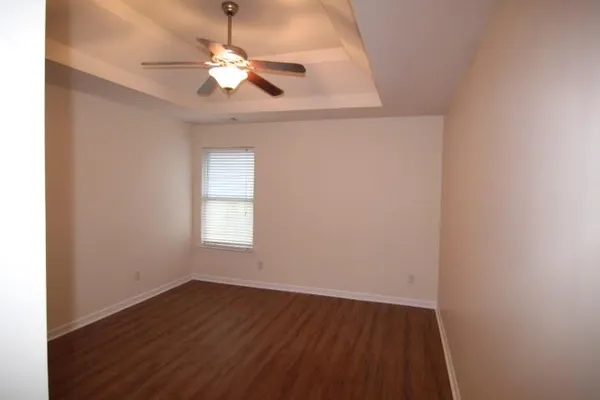 an empty room with wooden floor chandelier fan and windows