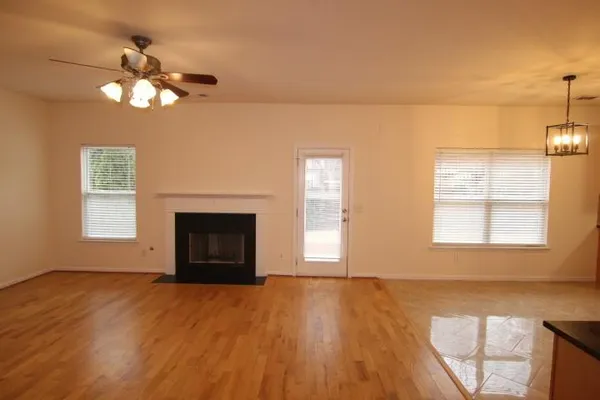 a view of an empty room with a window and wooden floor