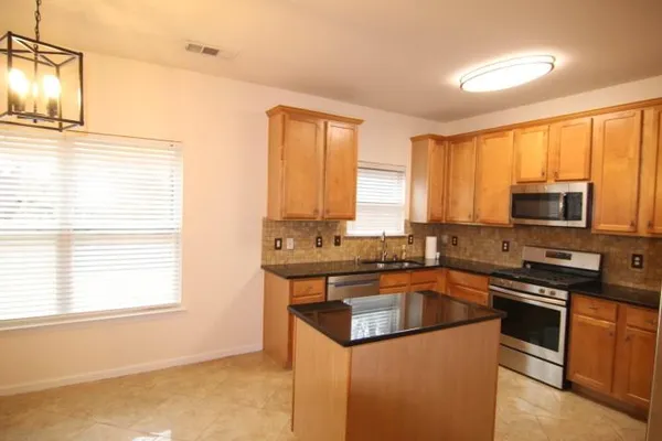 a kitchen with stainless steel appliances granite countertop a stove a sink and a microwave