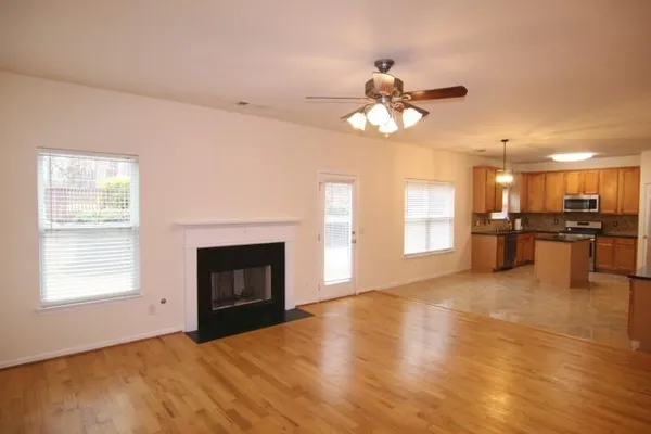 a view of a livingroom with a fireplace a ceiling fan and windows