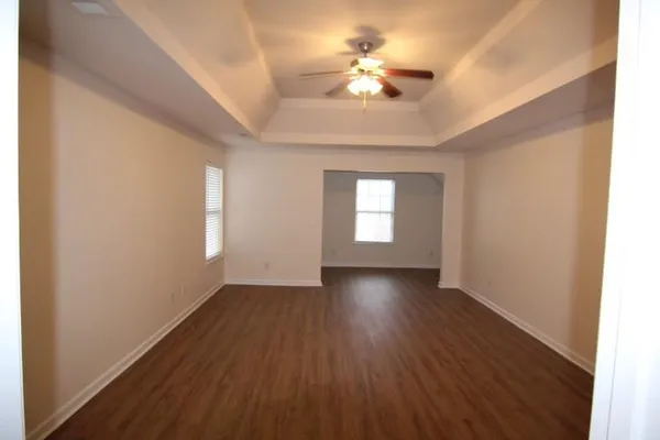 a view of an empty room with a window and wooden floor