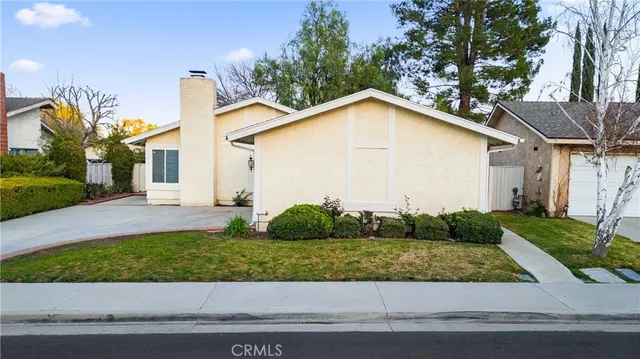 a view of a white house next to a yard and large trees