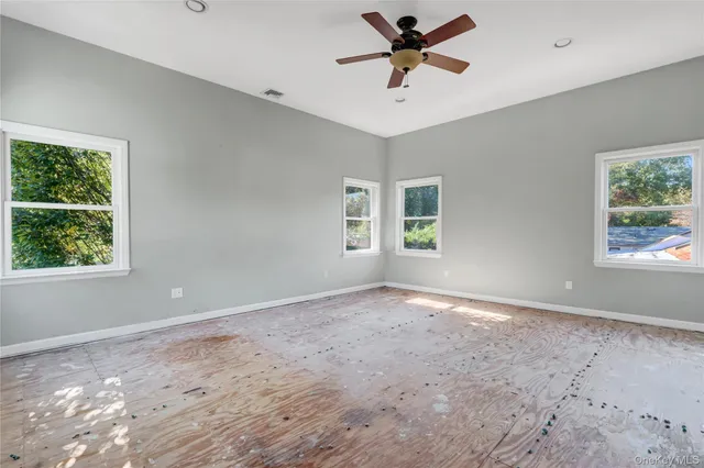 a view of a big room with windows and ceiling fan