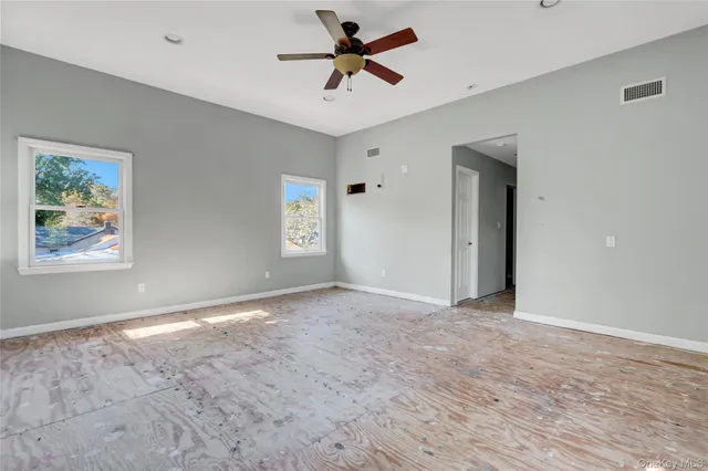 a view of an empty room with window and a ceiling fan