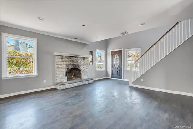 a view of an empty room with wooden floor fireplace and a window