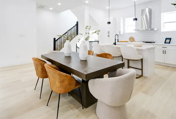 a living room with stainless steel appliances kitchen island granite countertop a table chairs and a refrigerator