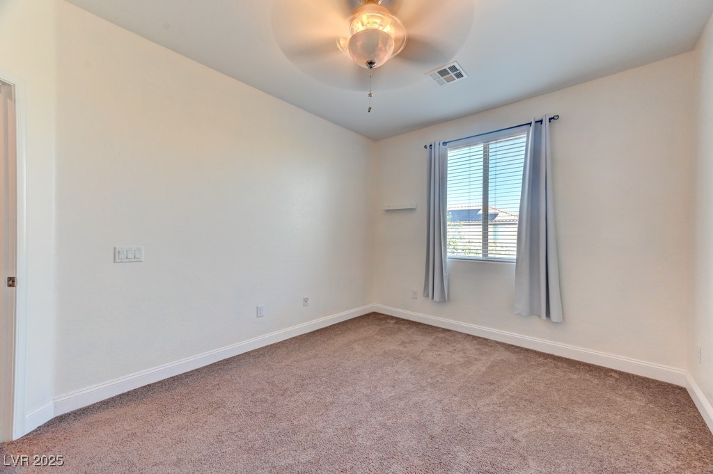 10281 Numaga Road Las Vegas, NV 89178 - Photo 18 of 41 Empty room with light carpet and ceiling fan