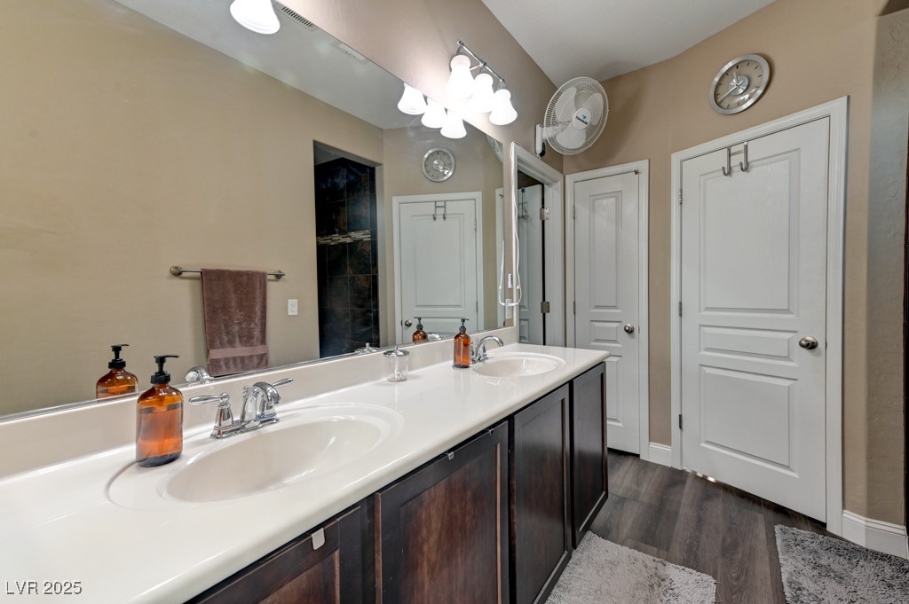 10281 Numaga Road Las Vegas, NV 89178 - Photo 32 of 41 Bathroom featuring double vanity, dark wood-style flooring, and a tile shower