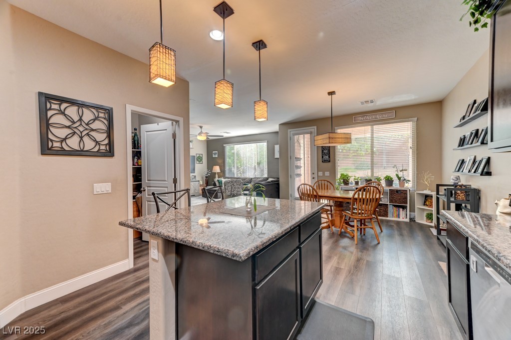 10281 Numaga Road Las Vegas, NV 89178 - Photo 4 of 41 Kitchen featuring light stone counters, decorative light fixtures, dark wood-type flooring, a kitchen island, and recessed lighting