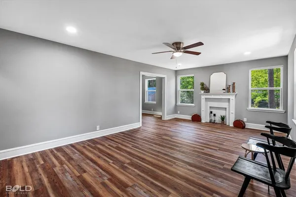 a view of a livingroom with wooden floor a ceiling fan and windows