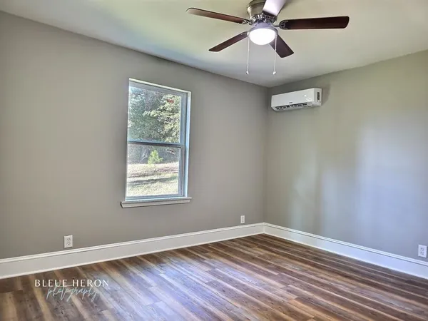 a view of an empty room with window and wooden floor