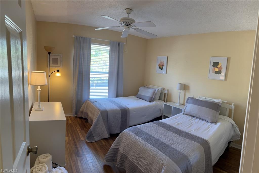 185 Grand Oaks Way, Unit R204 Naples, FL 34110 - Photo 6 of 18 a bedroom with two beds and a chandelier