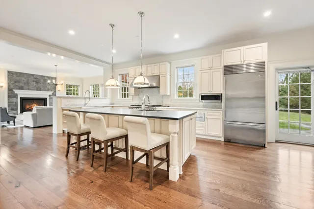 a kitchen with stainless steel appliances granite countertop a refrigerator a stove a sink and a dining table with wooden floor