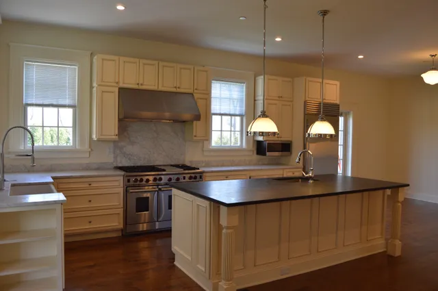 a kitchen with kitchen island granite countertop a stove a sink and a window