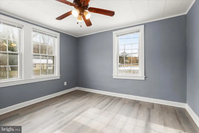 a view of an empty room with a window and wooden floor
