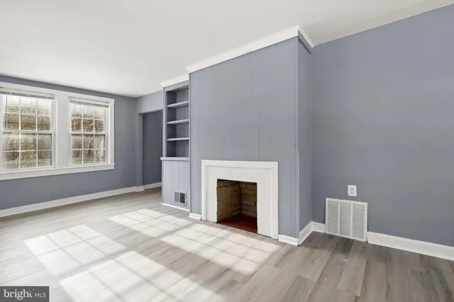 an empty room with windows and fireplace