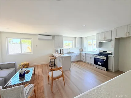 a kitchen with stainless steel appliances granite countertop a refrigerator a stove top oven a sink dishwasher and white cabinets with wooden floor