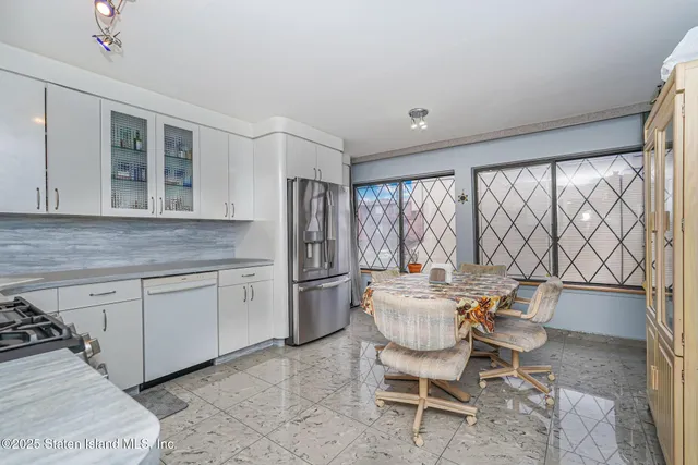 a kitchen with a dining table chairs and refrigerator