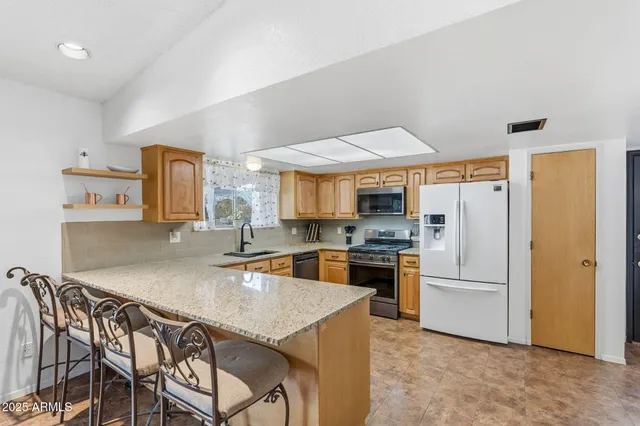 a kitchen with granite countertop a refrigerator stove top oven and sink