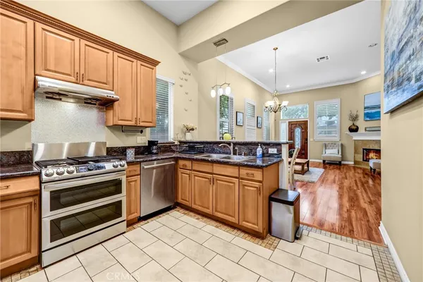 a kitchen with stainless steel appliances granite countertop a stove top oven a sink dishwasher and cabinets with wooden floor