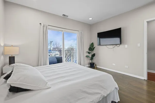 a bedroom with a large bed and a flat tv screen on dresser