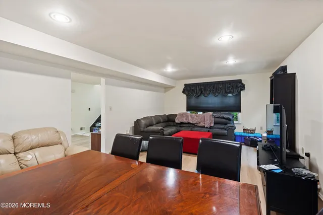 a living room with furniture a flat screen tv and a refrigerator