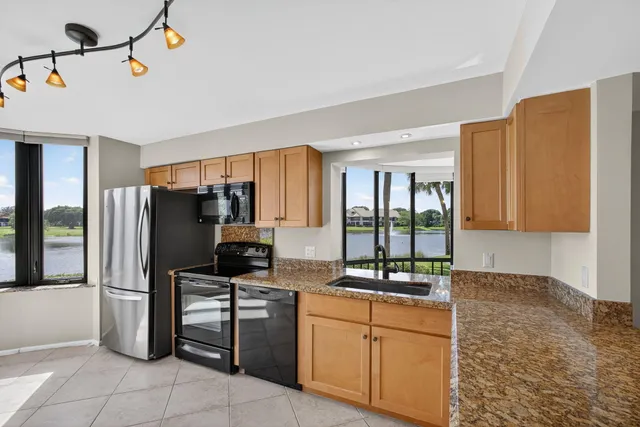 a kitchen with stainless steel appliances granite countertop a refrigerator a sink and dishwasher with a large window