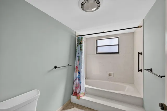 a bedroom with a bed a chandelier and a window