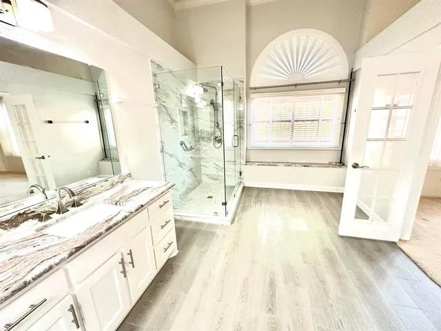 a spacious bathroom with a double vanity sink a mirror and a shower