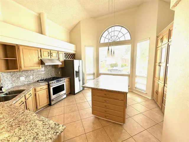 a kitchen with stainless steel appliances granite countertop a stove a sink and a microwave