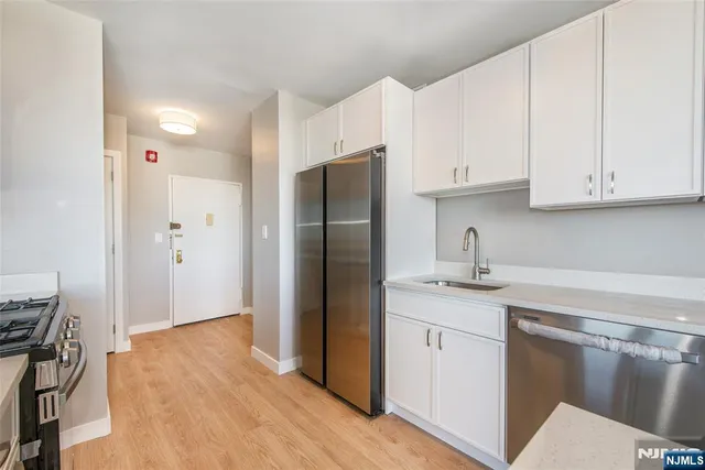a kitchen with stainless steel appliances granite countertop a refrigerator sink and white cabinets