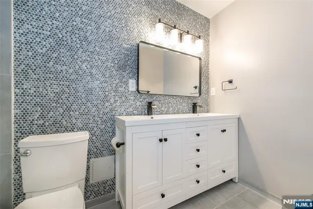 a bathroom with a granite countertop toilet sink and mirror