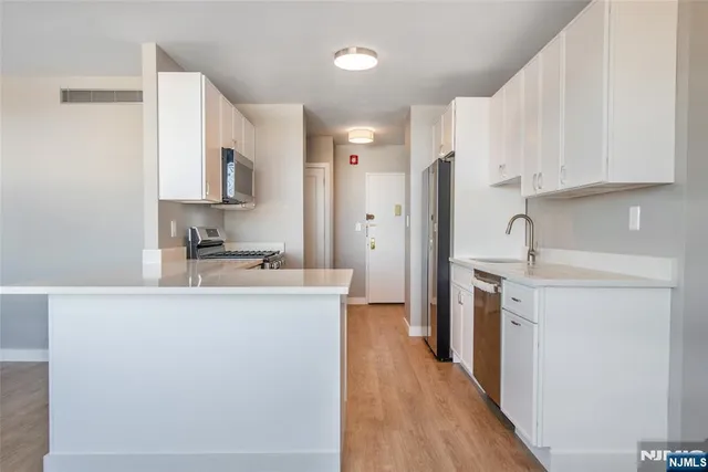 a kitchen with stainless steel appliances a refrigerator sink and white cabinets