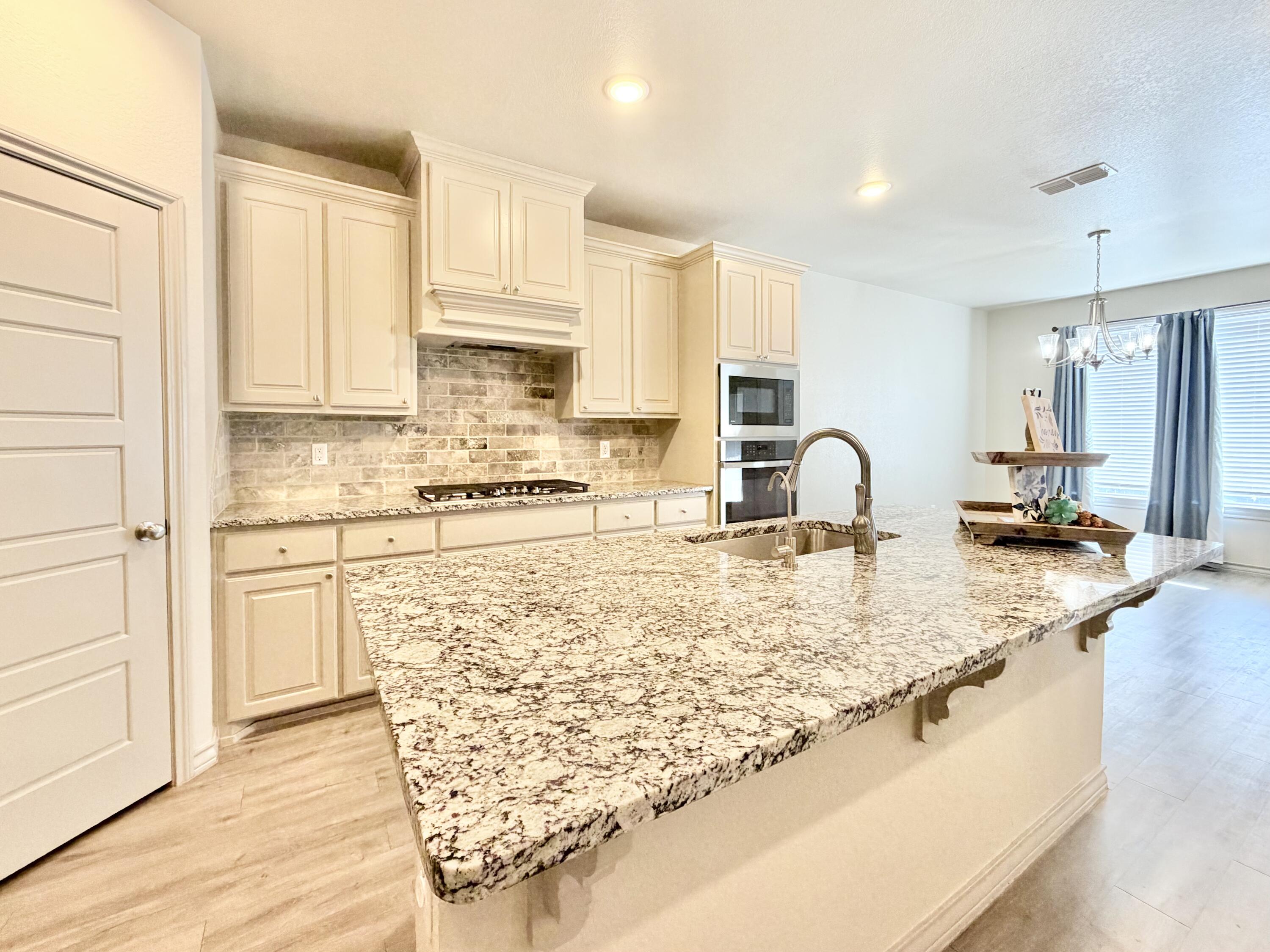 7611 61st Street Lubbock, TX 79407 - Photo 13 of 31 a kitchen with stainless steel appliances granite countertop a sink stove and cabinets