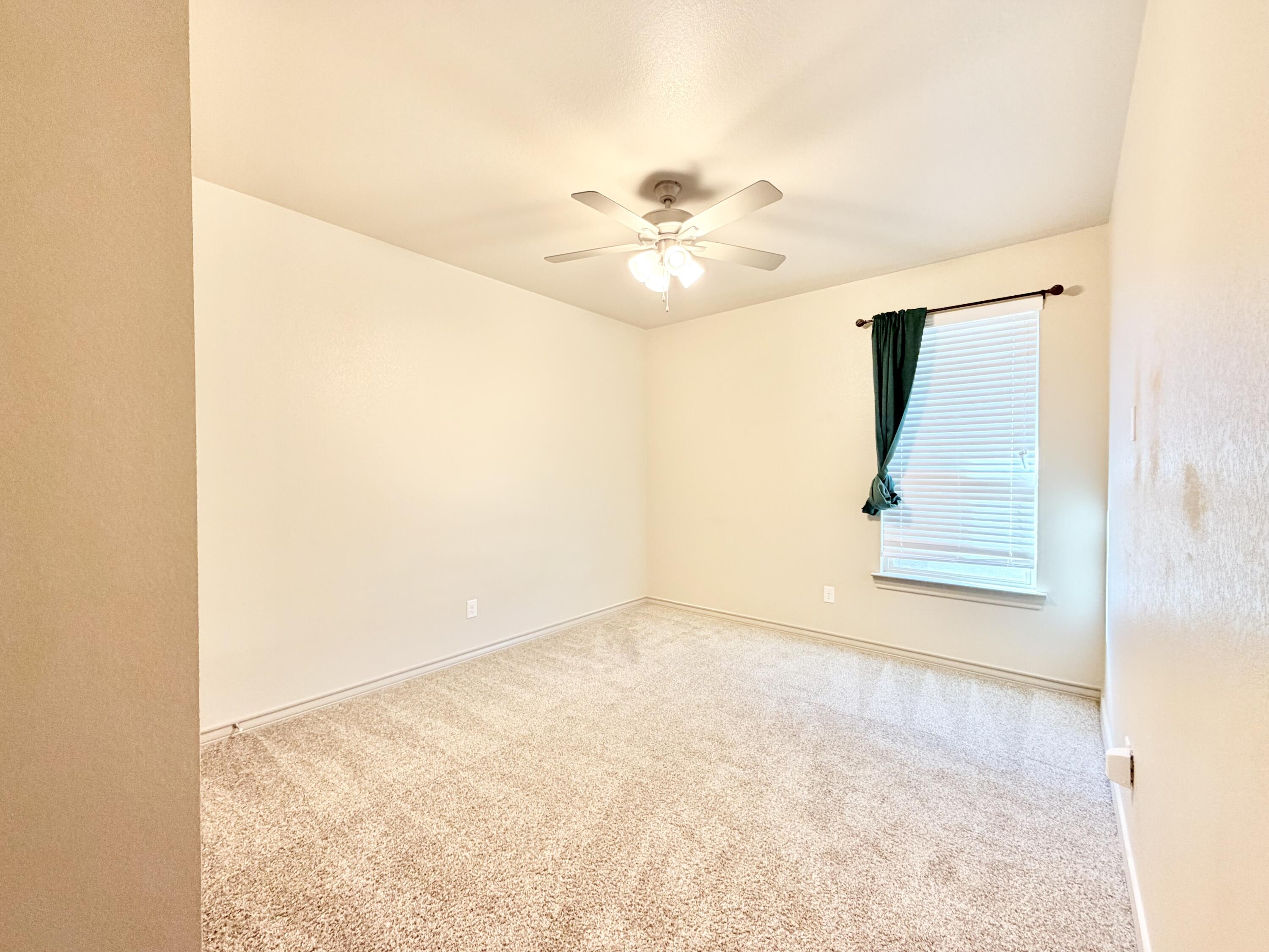 7611 61st Street Lubbock, TX 79407 - Photo 24 of 31 an empty room with a ceiling fan and wooden floor