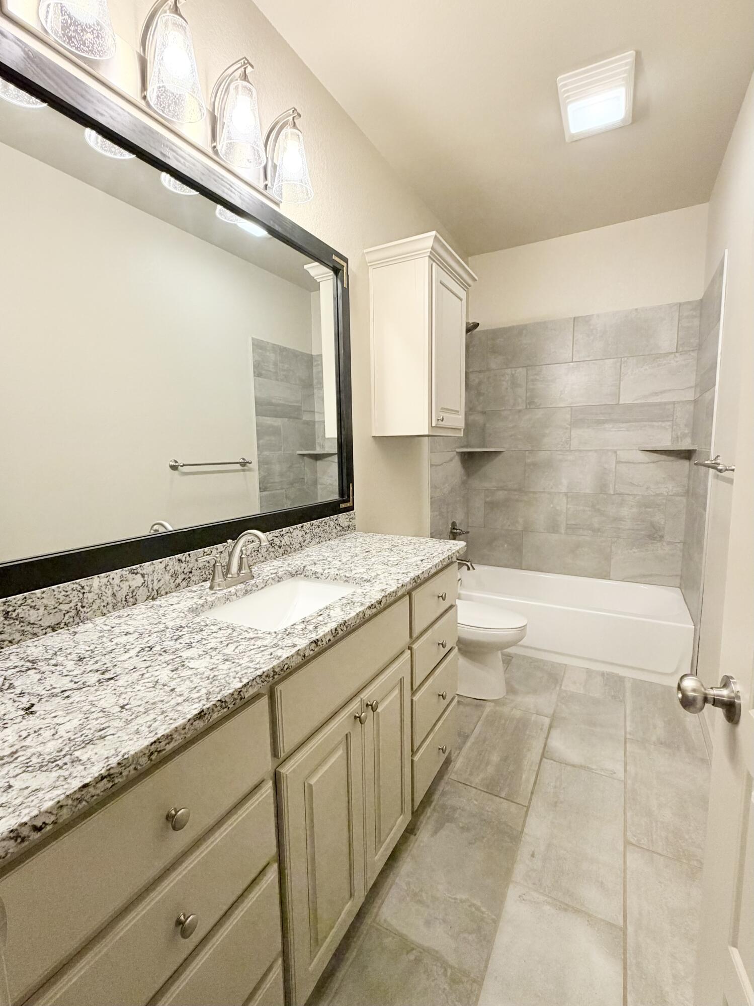 7611 61st Street Lubbock, TX 79407 - Photo 26 of 31 a bathroom with a granite countertop sink toilet and shower