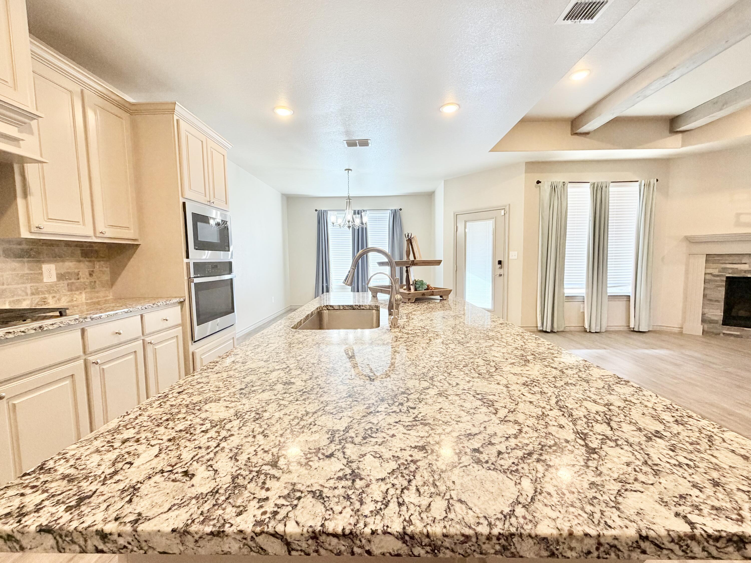 7611 61st Street Lubbock, TX 79407 - Photo 3 of 31 a large kitchen with kitchen island granite countertop a refrigerator and cabinets