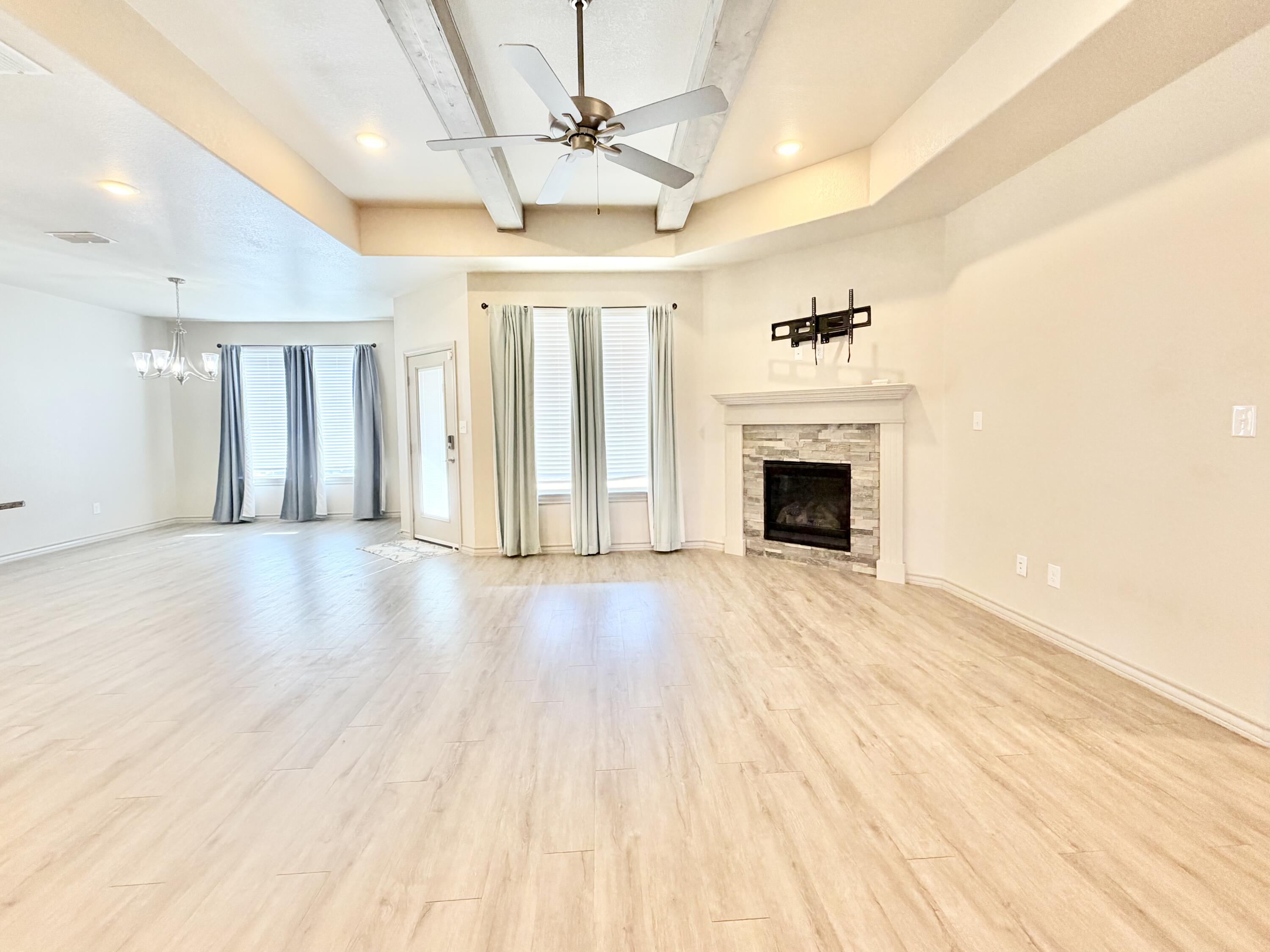 7611 61st Street Lubbock, TX 79407 - Photo 5 of 31 an empty room with wooden floor fireplace and windows