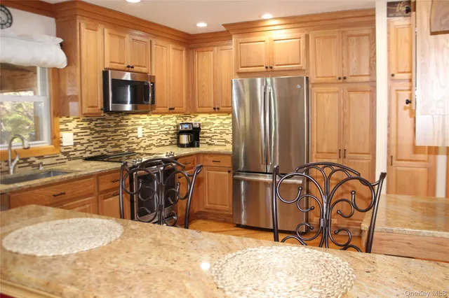 a kitchen with stainless steel appliances granite countertop a refrigerator a stove and a sink with granite countertops