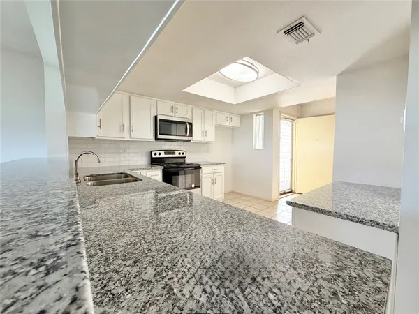 a kitchen with granite countertop a stove a sink and a microwave