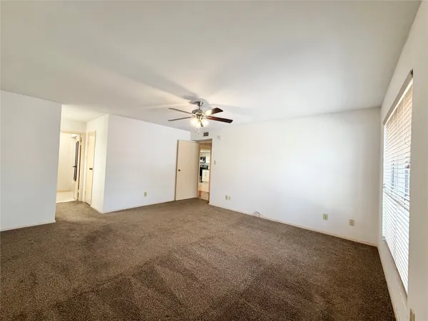 an empty room with windows and fan