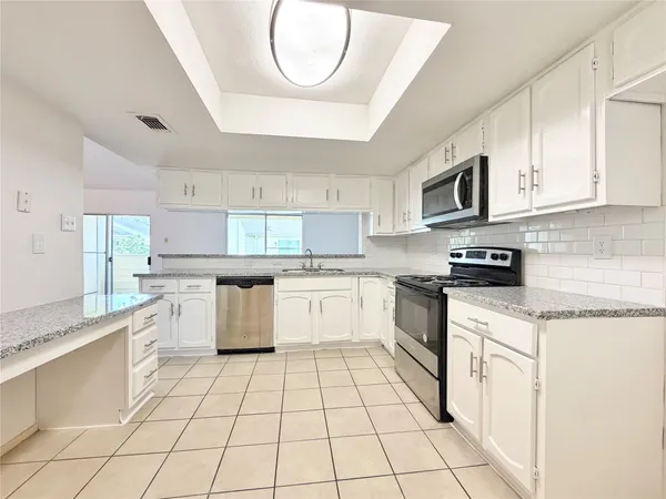 a kitchen with stainless steel appliances granite countertop a stove a sink and a microwave