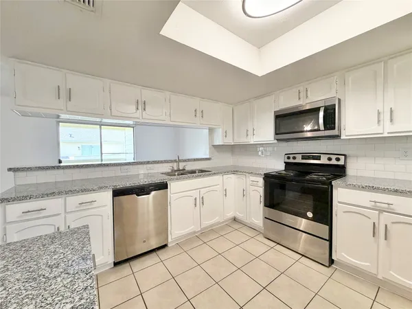 a kitchen with granite countertop white cabinets and appliances