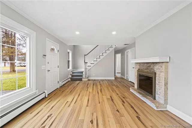 a view of empty room with wooden floor fireplace and windows
