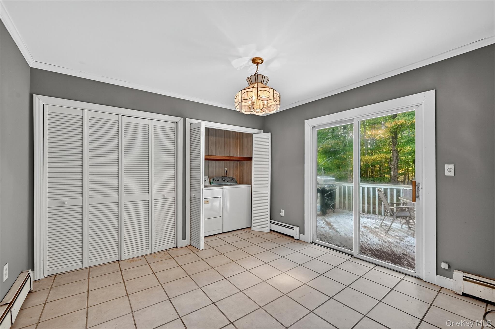 8 Haight Road Monroe, NY 10950 - Photo 19 of 40 Unfurnished dining area with a baseboard heating unit, light tile patterned flooring, a chandelier, and ornamental molding