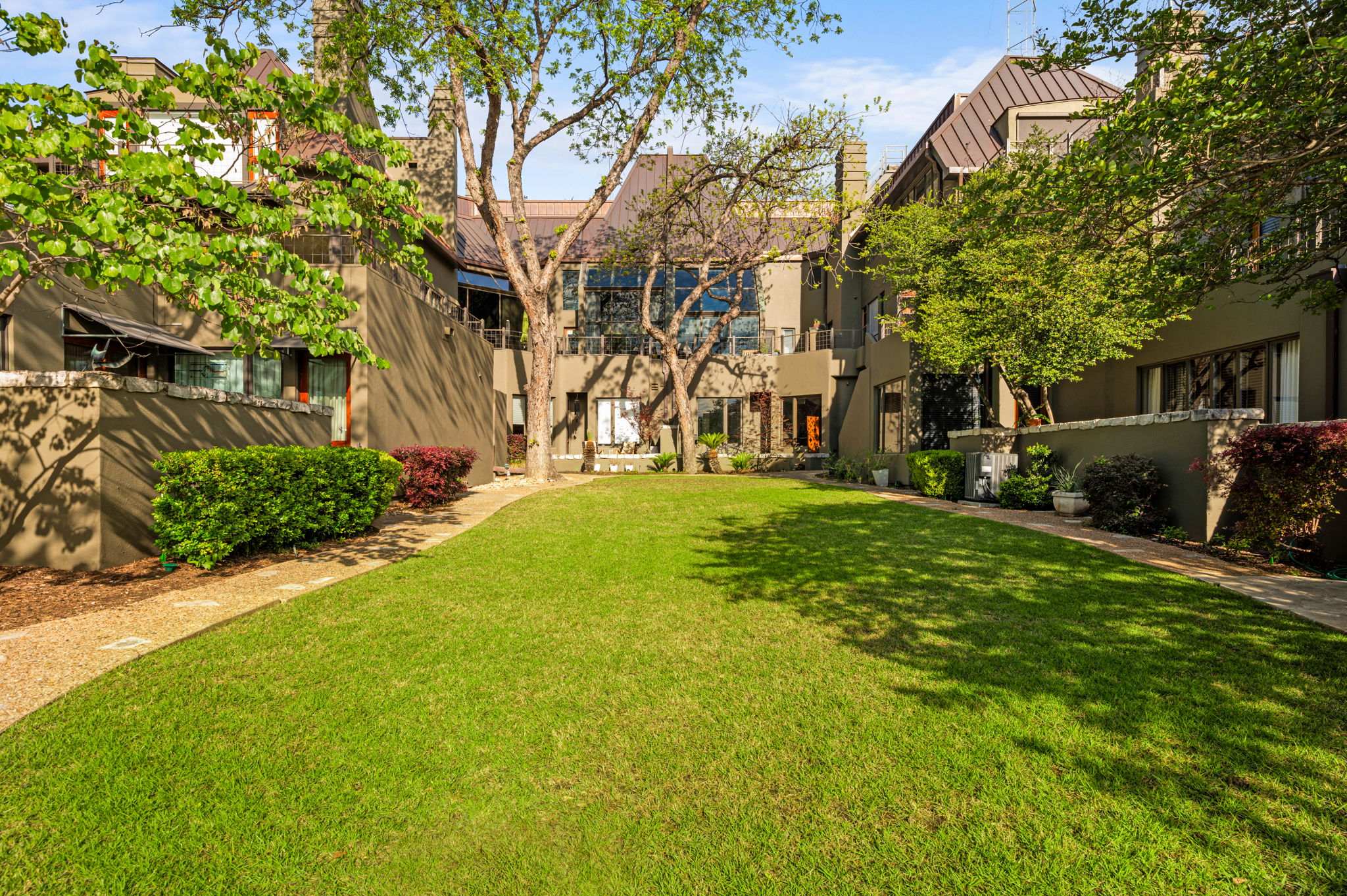 1111 West 12th Street, Unit 107 Austin, TX 78703 - Photo 8 of 38 Expansive green lawn with surrounding mature trees and landscaping