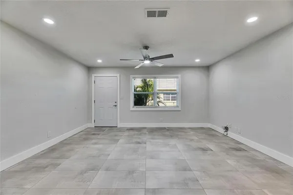 an empty room with windows and ceiling fan
