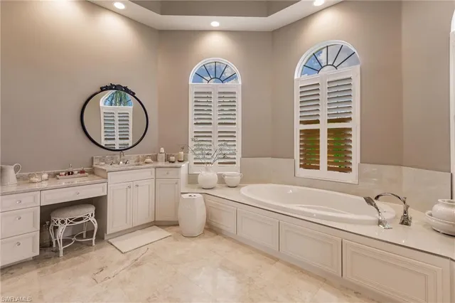 a bathroom with a two sinks mirror and a bathtub next to a window
