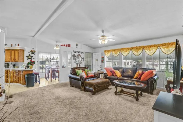 a living room with furniture a ceiling fan and a floor to ceiling window