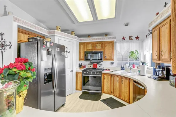 a kitchen with stainless steel appliances granite countertop a refrigerator a sink dishwasher and white cabinets next to a window